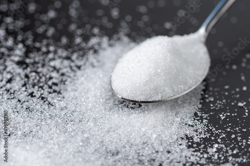 Close-up of spoon with sugar on the black table