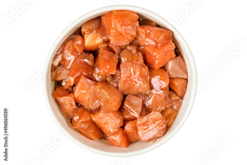 A bowl of sliced salmon in soy sauce on a white background. Top view.