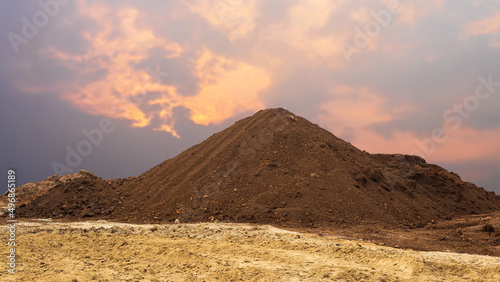 View of a large amount of brown loam loam piled up like mountains on yellow sand.