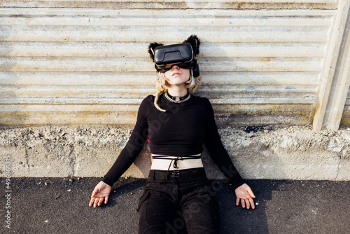 Young cyber dependence woman using 3D headset lying floor addicted augmented reality photo