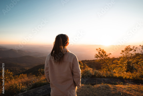 Woman looking at beautiful mountain valley in fog at sunrise and flare in summer, Travel and tourism. © oatawa