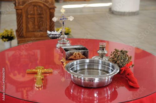 Fotografie Closeup shot of a gold cross, holy water, and religious things on a red table