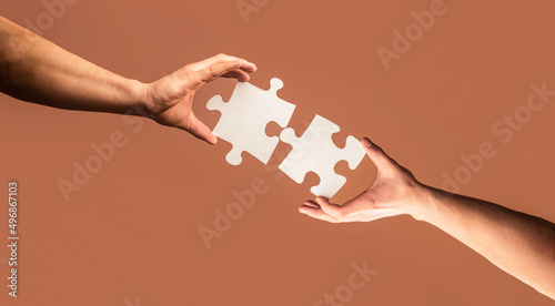 Holding puzzle. Closeup hand of connecting jigsaw puzzle. Business solutions, success and strategy concept. Two hands trying to connect couple puzzle piece on yellow background. Teamwork concept