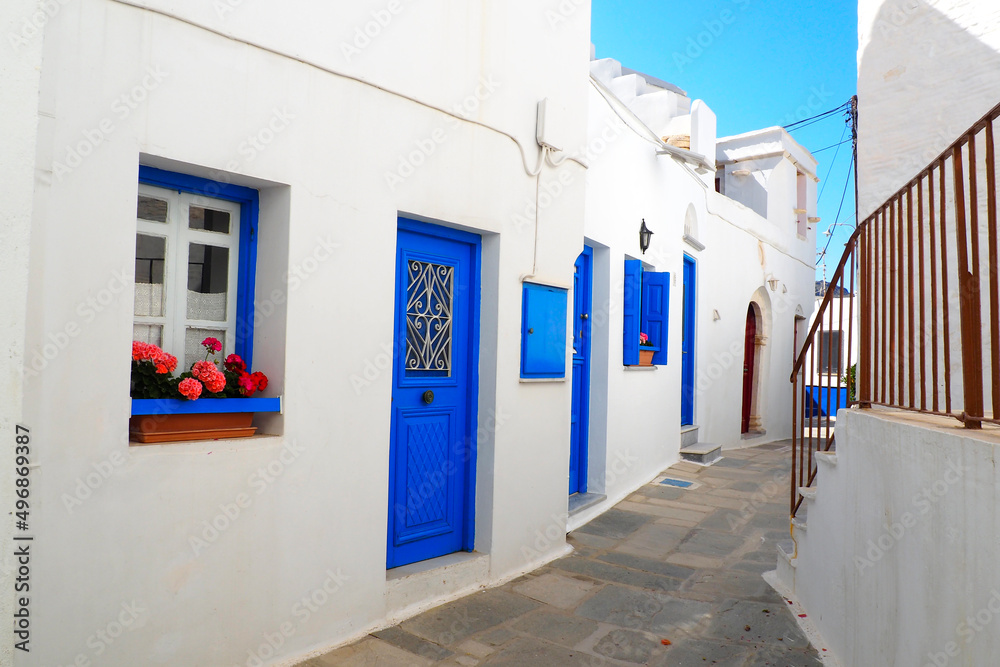 Fototapeta One of the charms of the Cyclades (here, in Pyrgos on the island of Tinos), in the heart of the Aegean Sea, are the narrow streets: white houses, colorful doors, flowery balconies and cobbled streets