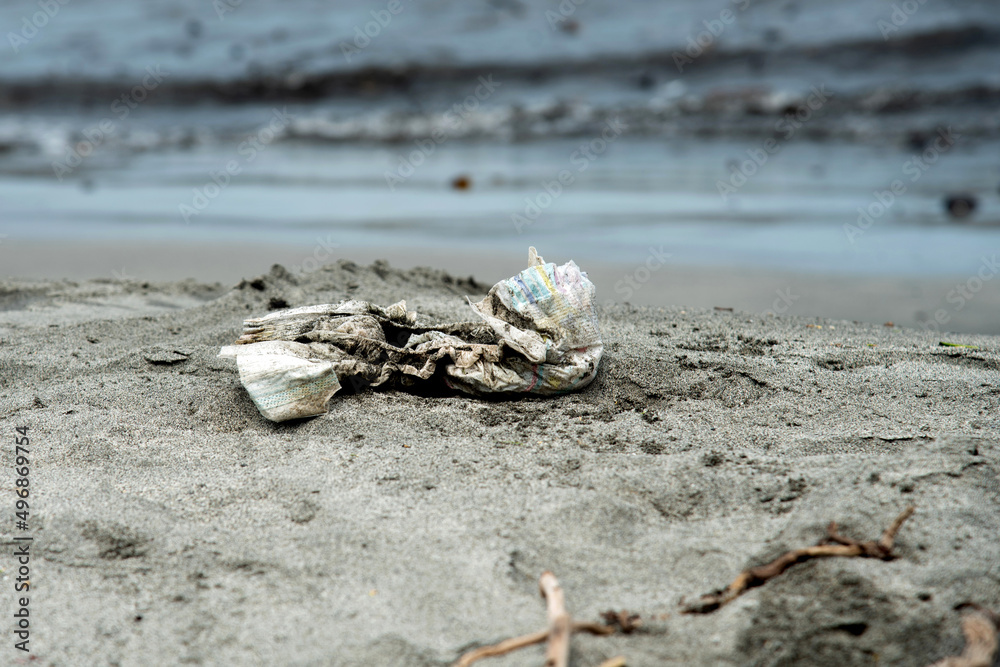 Dirty disposable baby diaper thrown on the sandy beach Diapers pollute