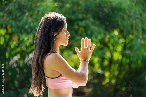 Side View of Young Woman Practicing Yoga Doing Mudra Gesture on a Green Park.Copy Space