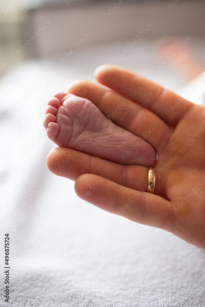 Tiny baby leg between mom's fingers selective focus Tiny baby leg between mom's fingers selective focus
