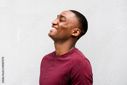 Close up profile happy young African American man laughing against gray background photo