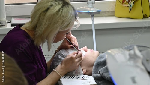 Eyelash extensions in a beauty salon. the master glues artificial eyelashes on the girl's eyelid.