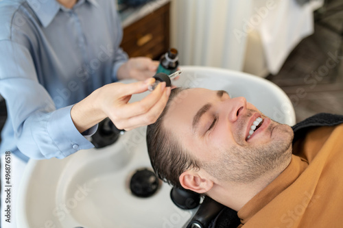 Beautician applying hair serum on mans head