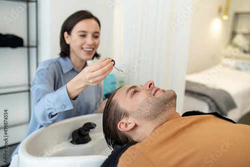 Beautician applying hair serum on mans head