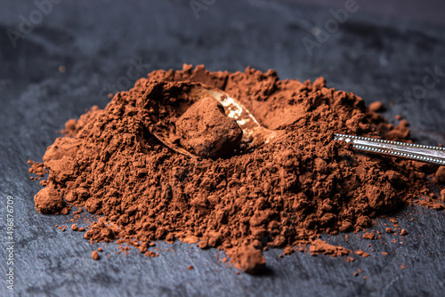 Cocoa powder on a black background. Ingredient for making chocolate. Spoon full of cocoa