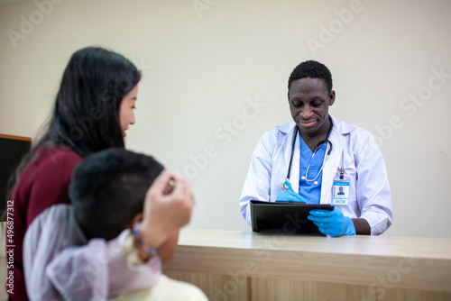 African pediatrician taking the patient's history and examining child boy patient with his mother.