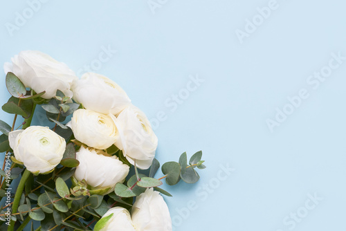 Bunch of white ranunculus flowers on blue background. Mothers Day, Valentines Day, birthday concept