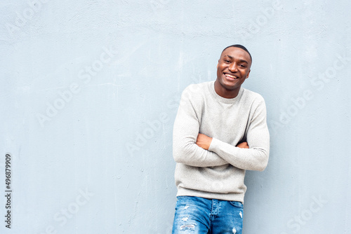 portrait smiling African american man leaning against wall with arms crossed