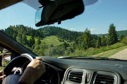 Driver behind the wheel of a car with a view of the beautiful mountains in the Carpathians, photo of hands behind the wheel