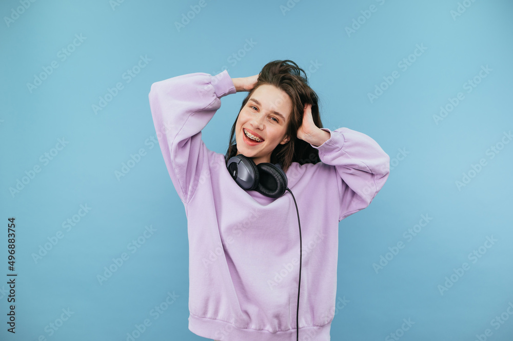 Smiling woman in purple sweatshirt stands on a blue background and poses for the camera with a smile on his face. Smiling woman in purple sweatshirt stands on a blue background and poses for the camera with a smile on his face.