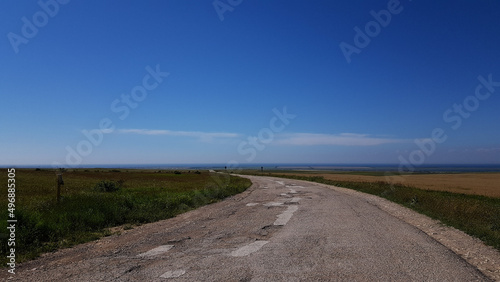 a dirt road through the fields leads to the sea. clear skies in sunny weather in summer in the south