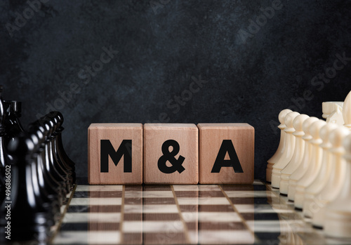 Chessboard with chess pieces and wooden blocks with the word mergers and acquisitions photo