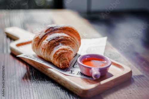 Croissant placed on paper with honey in a small cup ready to eat.