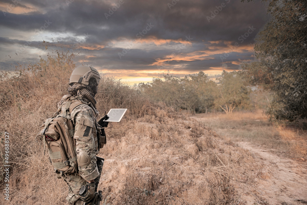 Soldier using map on tablet for orientation at forest Soldier using map on tablet for orientation at forest