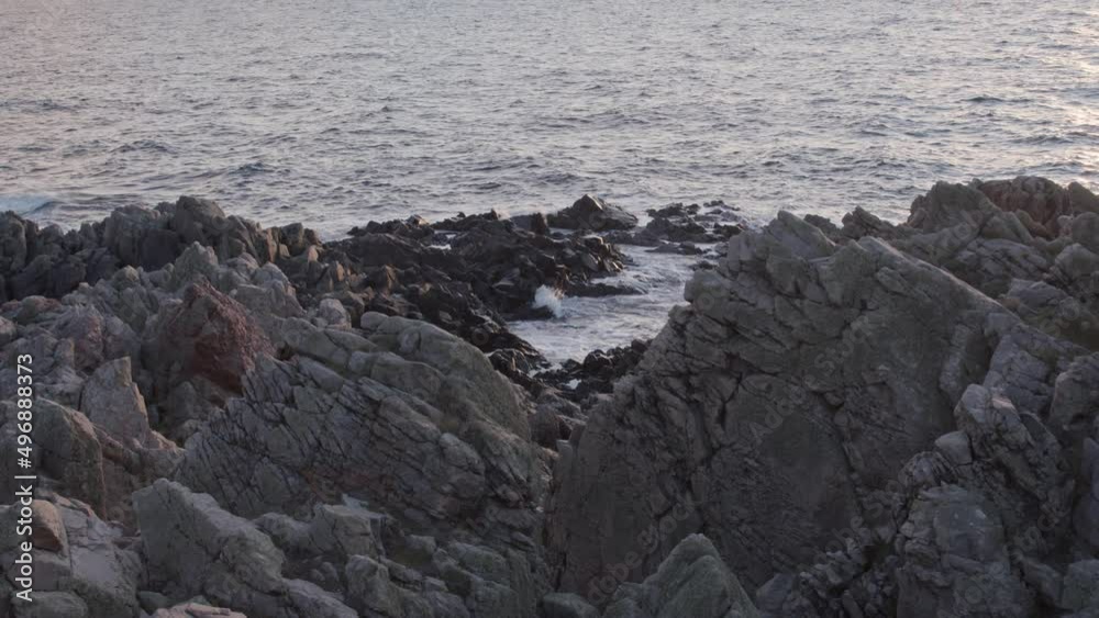 Waves rolling into rocky cape at sunset in slow motion. Static horizontal shot. Waves rolling into rocky cape at sunset in slow motion. Static horizontal shot.