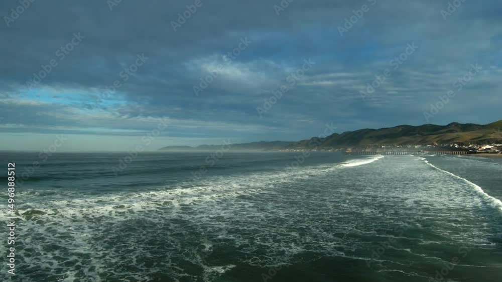 Low altitude high-speed drone flying over the ocean waves and turning to view the picturesque beach, landscape, mountains and shore Low altitude high-speed drone flying over the ocean waves and turning to view the picturesque beach, landscape, mountains and shore