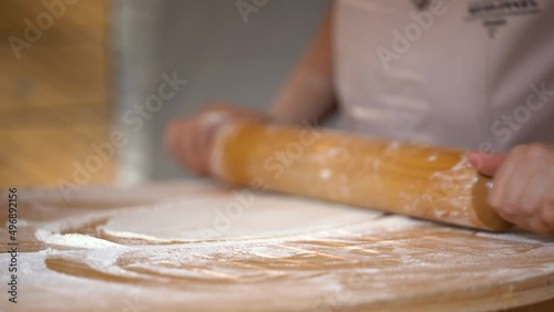  Woman' s hands rolling dough for preparing bread, cake, pizza or else. Professional female hands rolling dough.   photo