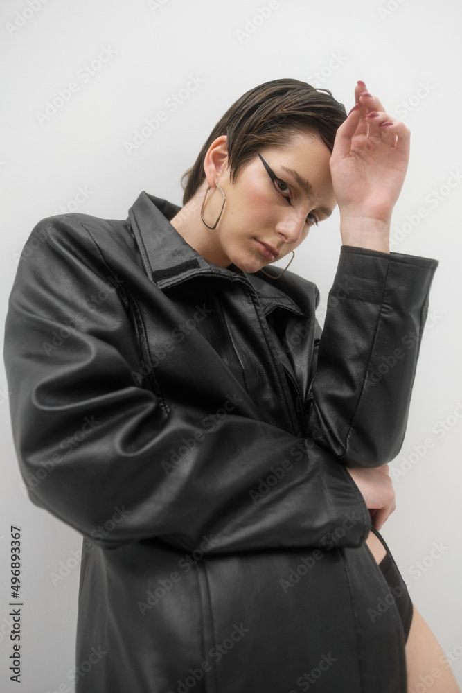 Fashion photo shoot in studio, on white background. Young beautiful woman emotionally and dramatically poses in black vintage cloak on a naked body. Short brown hair, large black eye arrows. Fashion photo shoot in studio, on white background. Young beautiful woman emotionally and dramatically poses in black vintage cloak on a naked body. Short brown hair, large black eye arrows.