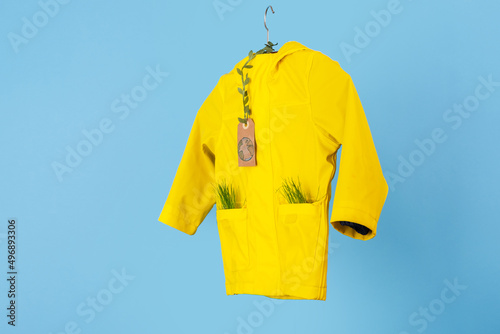 Rainwear recycling. used outerwear. Ecological and sustainable lifestyles. mock up yellow raincoat on a blue background. 