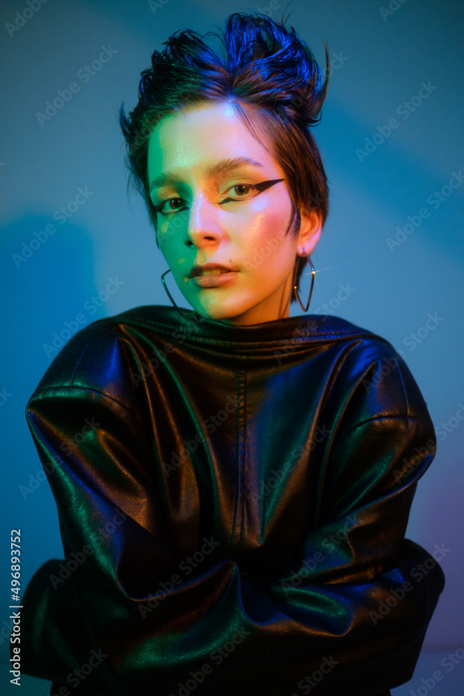 Fashionable portrait of emotional young beautiful woman with raised up short hair. Colorful fashionable neon light, blue, yellow, green. Fashionable portrait of emotional young beautiful woman with raised up short hair. Colorful fashionable neon light, blue, yellow, green.