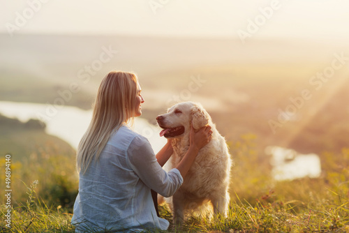 Obraz na płótnie Special and serene moment as a girl is lovingly hugging her Golden Retriever Dog against the sunsetting sky. w salonie