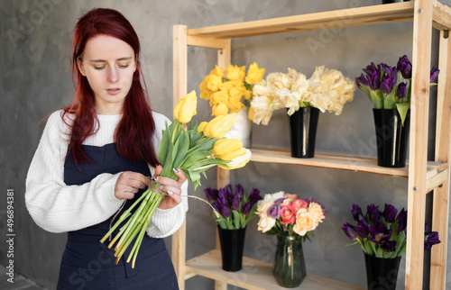 European flower shop concept. A female florist creates a beautiful bouquet of spring tulip flowers. Beautiful fresh bouquet. Education, master classes and floristry courses.