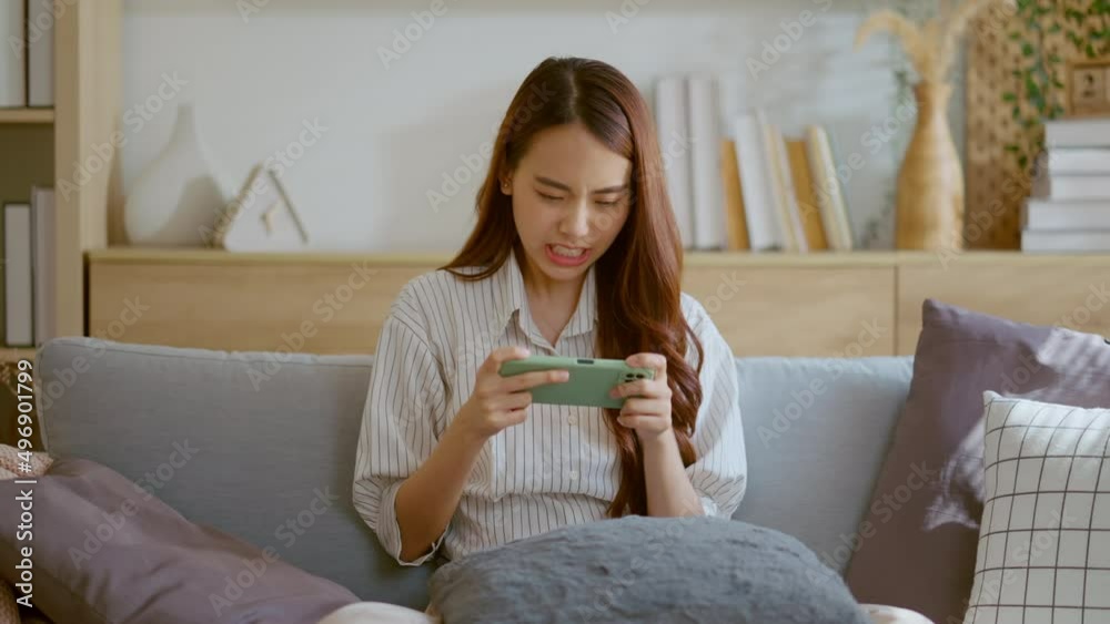 happiness asian young female enjoy playing and competition game smartphone mobile online on sofa in living room home interior background,asia woman esport playing game streaming home isolate ideas happiness asian young female enjoy playing and competition game smartphone mobile online on sofa in living room home interior background,asia woman esport playing game streaming home isolate ideas