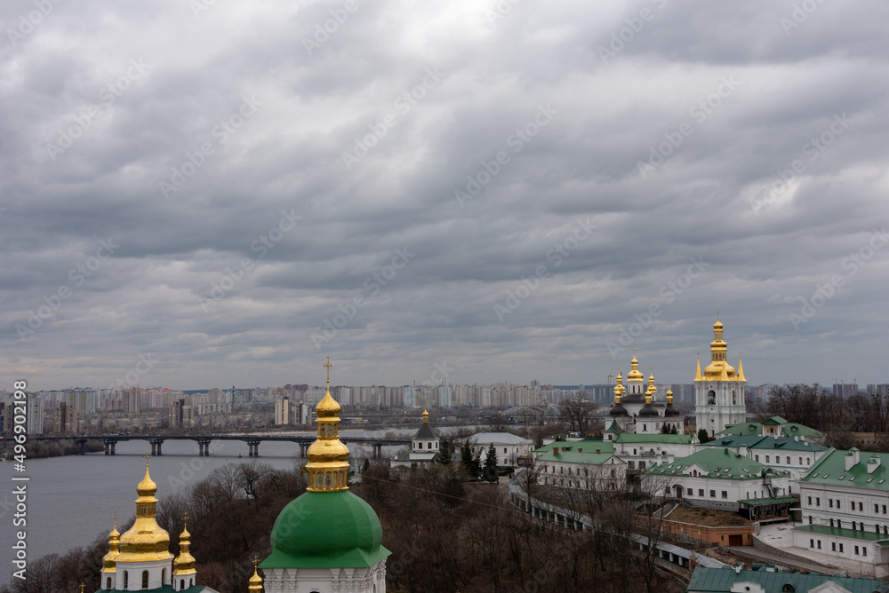 Kyiv Pechersk Lavra under cloudy sky. Dnipro river in the background. 