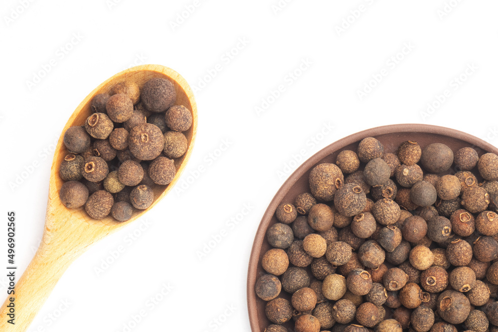 Spice Allspice in wooden spoon diagonally and clay plate on white background. Flat lay. Healthy eating concept Spice Allspice in wooden spoon diagonally and clay plate on white background. Flat lay. Healthy eating concept
