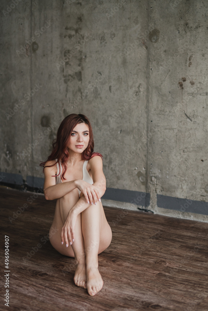 Naklejka premium Portrait of young pretty caucasian woman with natural makeup wearing light body in minimalistic loft interior. Youth, freshness, beauty, happiness, emotions concept.