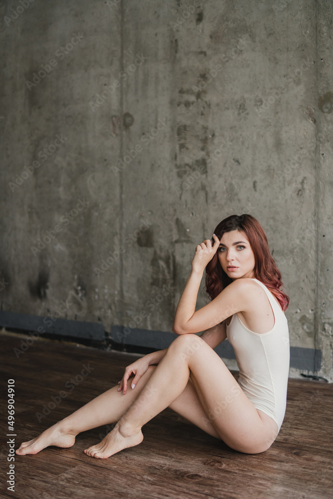 Naklejka premium Portrait of young pretty caucasian woman with natural makeup wearing light body in minimalistic loft interior. Youth, freshness, beauty, happiness, emotions concept.