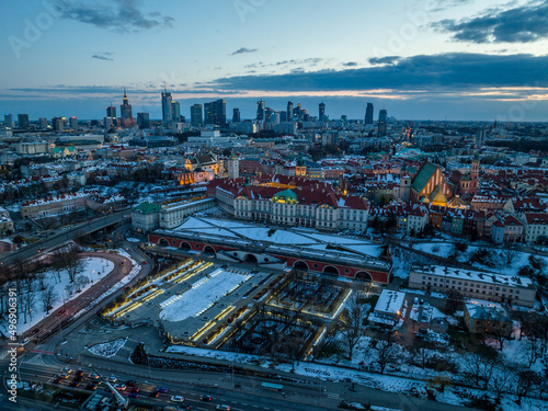 Widok na zamek królewki i stare miasto w Warszawie z drona, w tle wieżowce, zaśnieżone dachy, zachód słońca