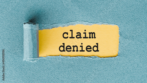 Claim Denied. phrase on yellow background under torn blue paper. Insurance and Warranty concept.