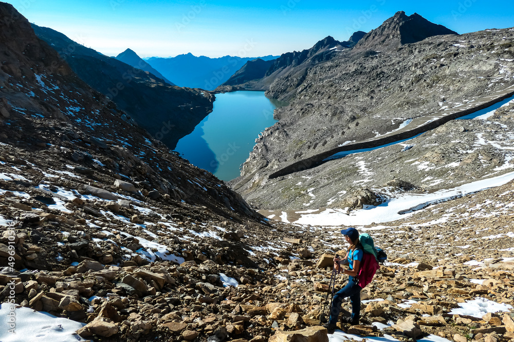 Woman with big backpack hiking with a scenic view on the mountains of Hohe Tauern Alps in Carinthia, Austria, Europe. A lake and water reservoir in the moelltaler glacier. Hohe Tauern National Park Woman with big backpack hiking with a scenic view on the mountains of Hohe Tauern Alps in Carinthia, Austria, Europe. A lake and water reservoir in the moelltaler glacier. Hohe Tauern National Park
