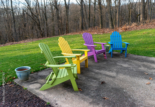 Adirondack chairs sit on a patio in early Spring in Hershey PA. Purple, Green, Yellow, and Blue Chairs look inviting on this nice Spring Day  Waiting for Temperatures to rise so they can be used again photo