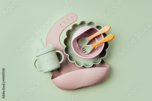 Photos Brown silicone baby bib and with plate and drinking cup on green background