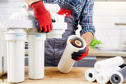 Plumber installs or change water filter. Replacement aqua filter. Repairman installing water filter cartridges in kitchen. Installation of reverse osmosis water purification system.
