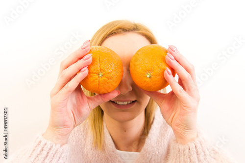 Close-up portrait of attractive healthy young woman holding oranges isolated on white background