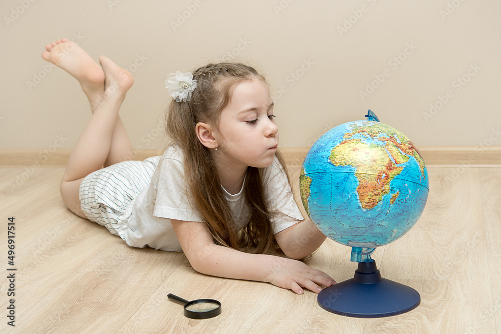little girl lies on the floor and carefully examines the globe little girl lies on the floor and carefully examines the globe