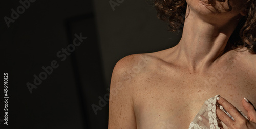 Woman with pigmentation and freckles on the body close-up on a dark background