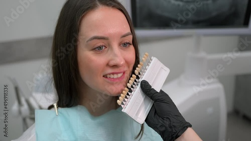 Dentist at work in dental clinic. Matching the shades of the implants using shade guide. Preparation for teeth whitening or implantation in dental office.