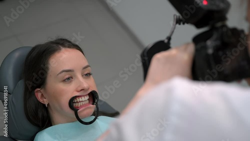 Dentist at work, dental clinic. Young woman doctor taking pictures of patient's teeth and jaw after successful treatment