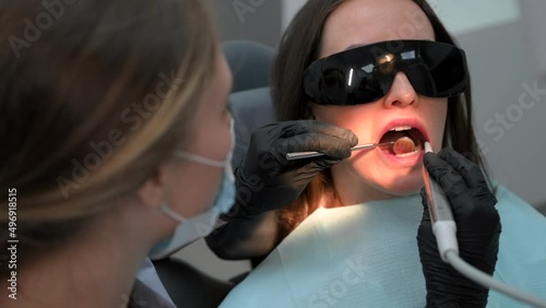 Woman dentist at work. Dental treatment in a modern dental clinic. Female patient in sunglasses